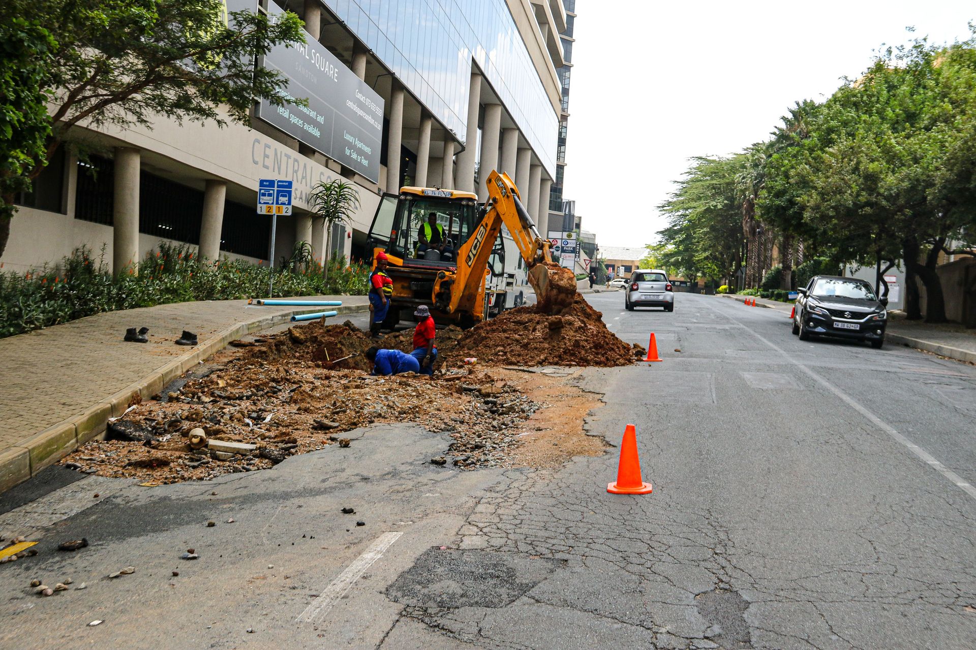 A daytime road construction scene in Sandton with workers and equipment.